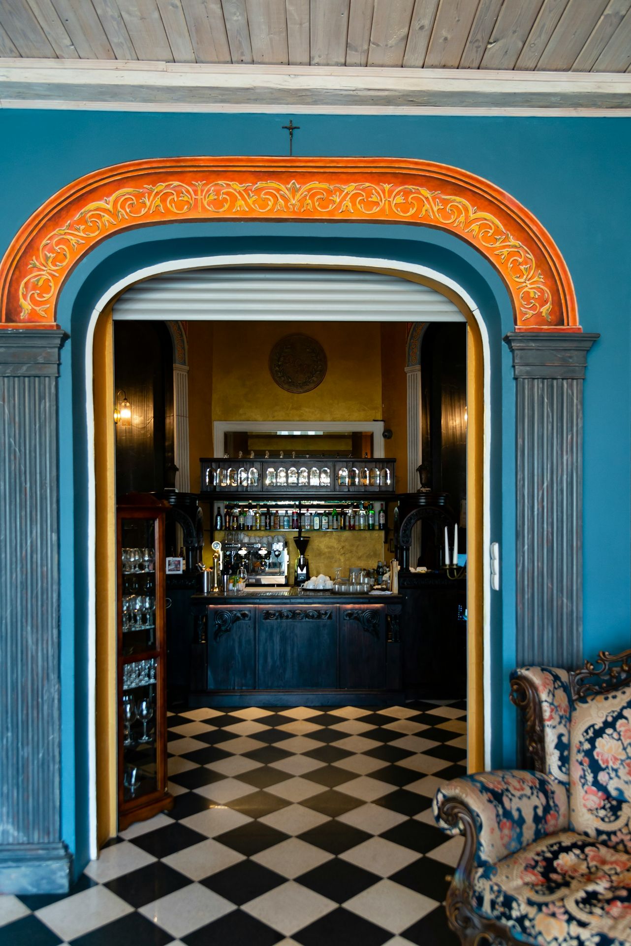 Ornate doorway leads to a bar with checkered floor.